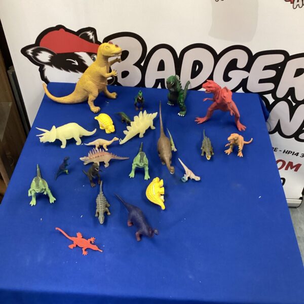 Colourful collection of plastic dinosaur toys on a dark surface.