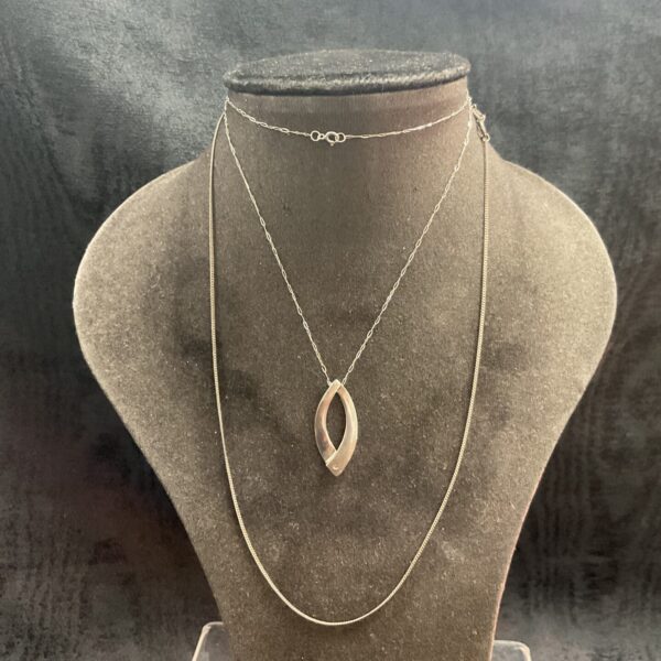 Silver chain necklaces with a crossover pendant design.
