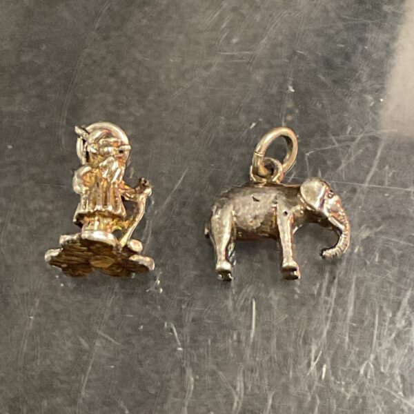 Vintage silver charms featuring a figure and elephant.