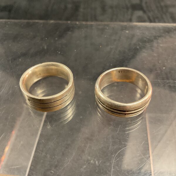 Pair of chunky 925 silver rings on a white surface.