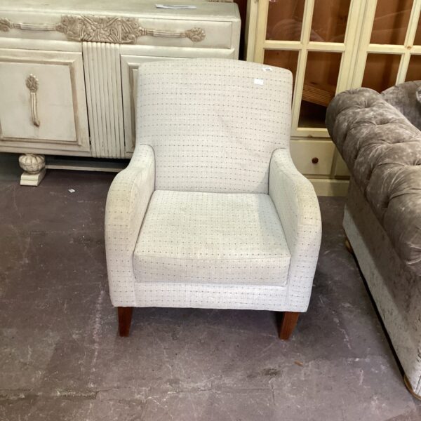 Vintage upholstered accent chair with neutral fabric and tapered legs.