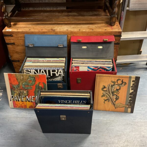 Three vintage vinyl record cases stacked on a wooden surface.
