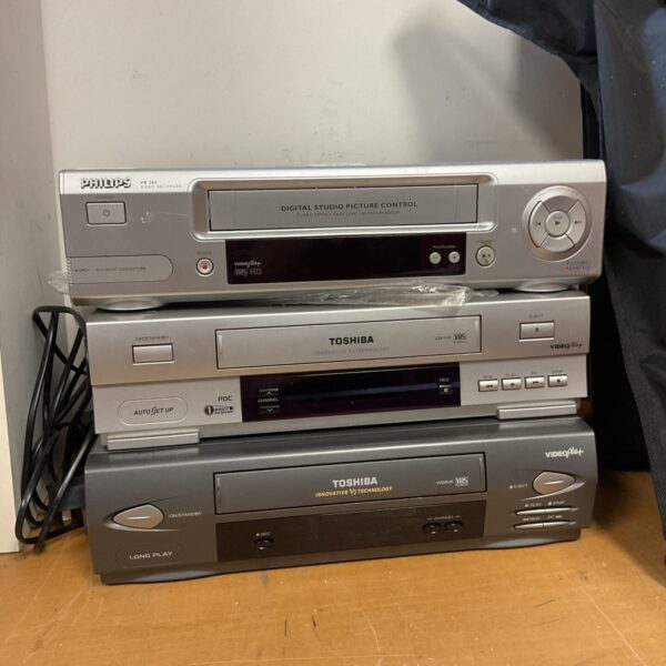 Front view of a lot of three vintage VHS recorders.