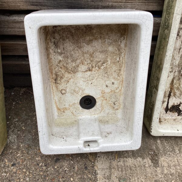 Front view of a vintage ceramic farmhouse sink with faucet holes.