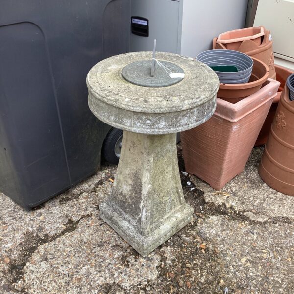 Weathered stone sundial in a garden setting.