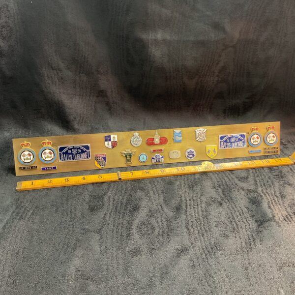 Vintage brass bar displaying enamel motor racing badges, including MG.