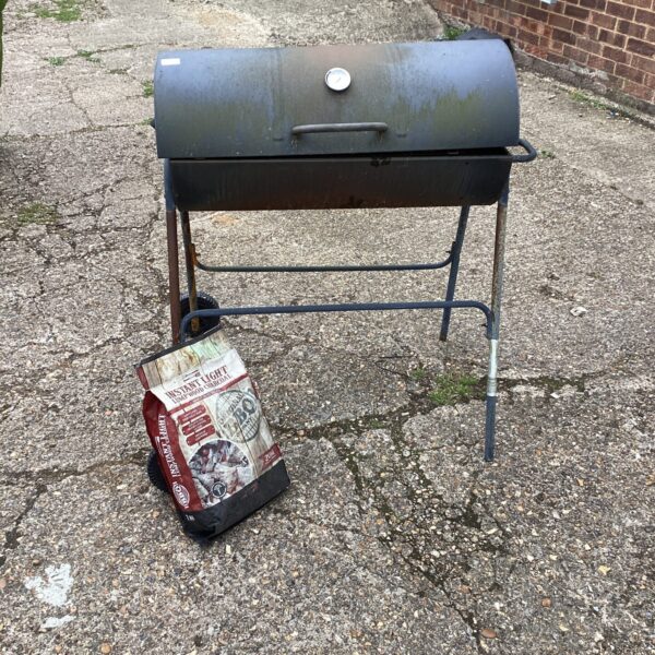 Vintage barrel BBQ grill in a garden setting.