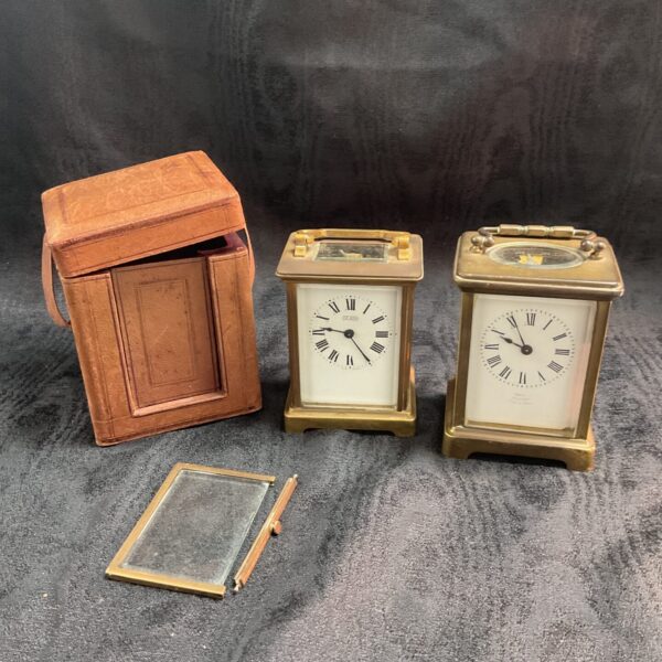 Vintage carriage clock pair with travel case, antique timepieces.