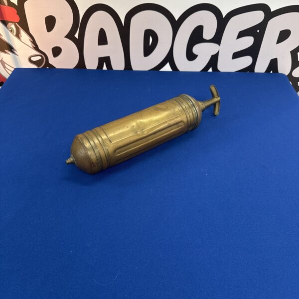 Vintage brass Pyrene fire extinguisher on blue background.