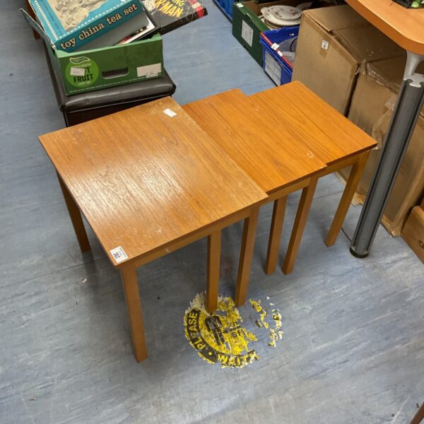 Set of three teak nesting tables in warm honey tone.