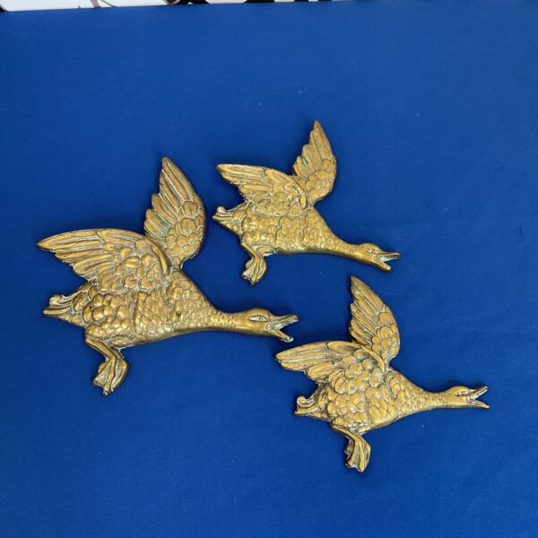 Set of three vintage brass wall ducks for retro home decor.