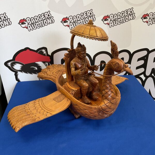 Vintage carved wooden deity on bird sculpture, detailed folk art.