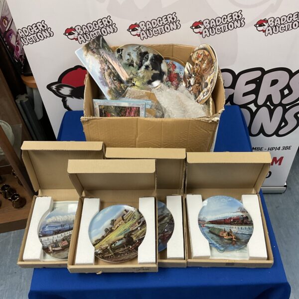 Box of assorted collectors plates including train and cat designs.
