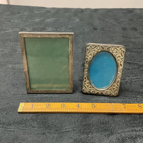 Antique silver and whitemetal picture frames on a dark surface.