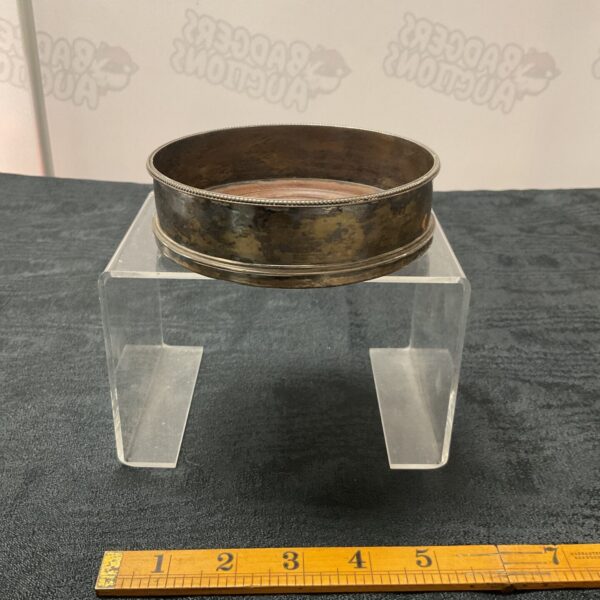 Antique Victorian silver wine coaster on display.