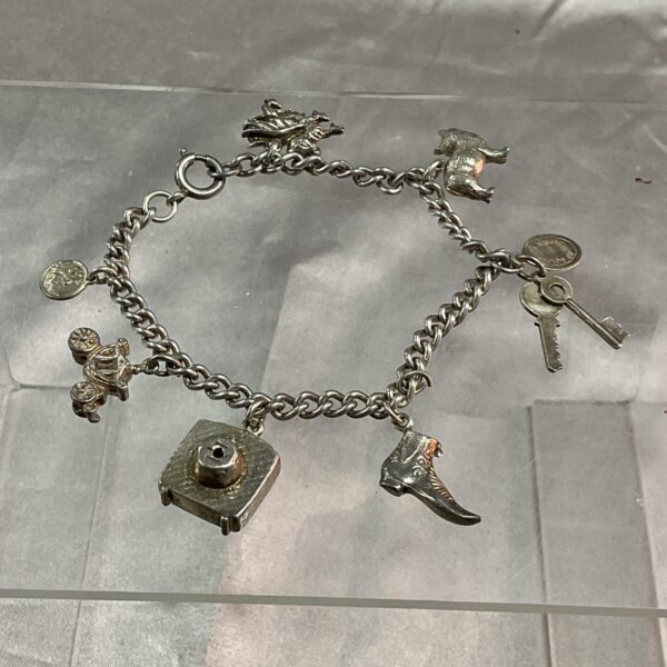 Close-up of a vintage silver charm bracelet with detailed novelty charms.