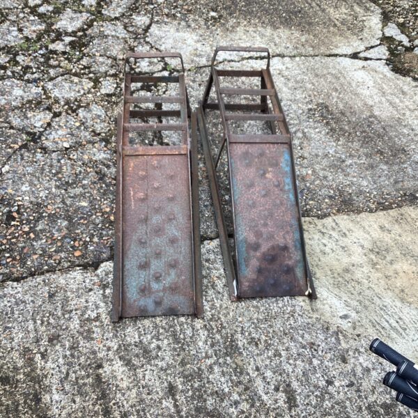 Pair of vintage steel car ramps for vehicle maintenance.
