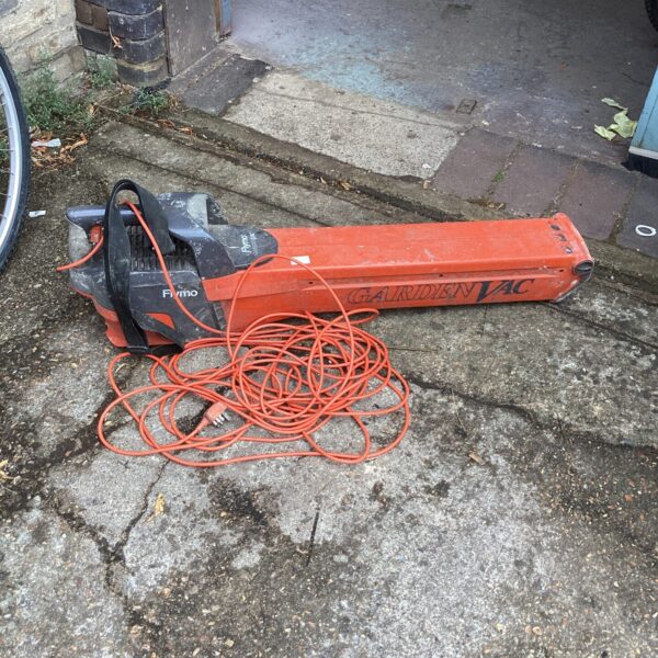 Side view of a used Flymo electric lawn vac with orange cable.