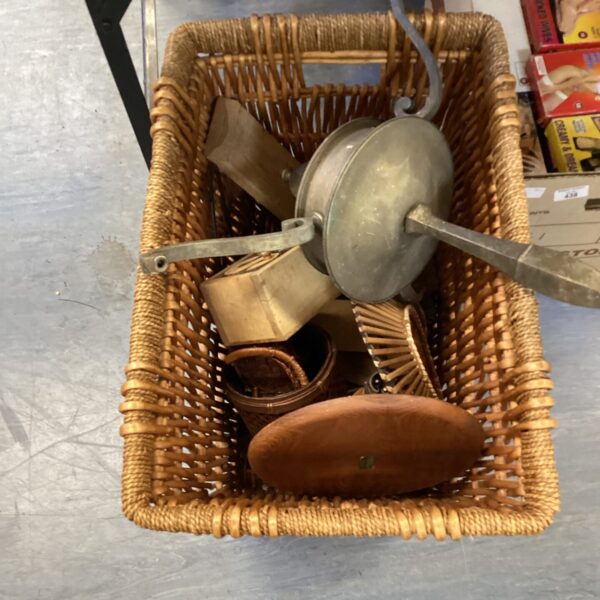 Vintage wicker basket filled with metal kitchenware and pots.