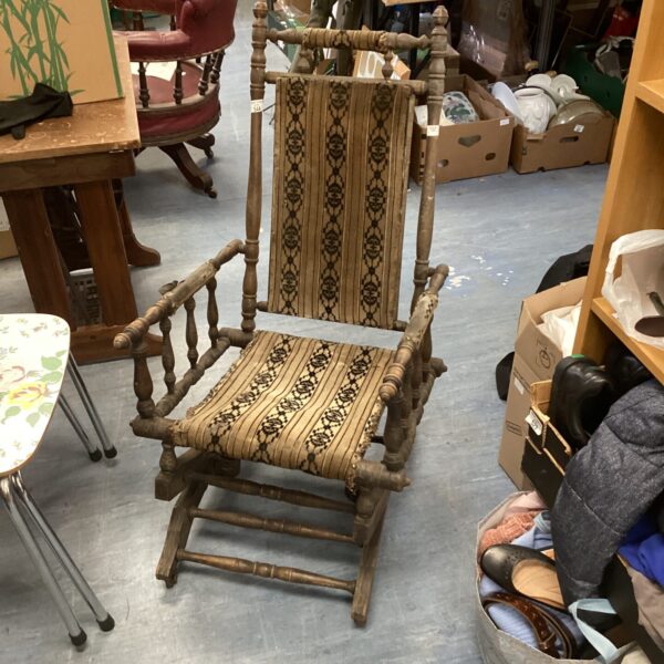 Antique Victorian rocking chair with spindle back and worn upholstery.