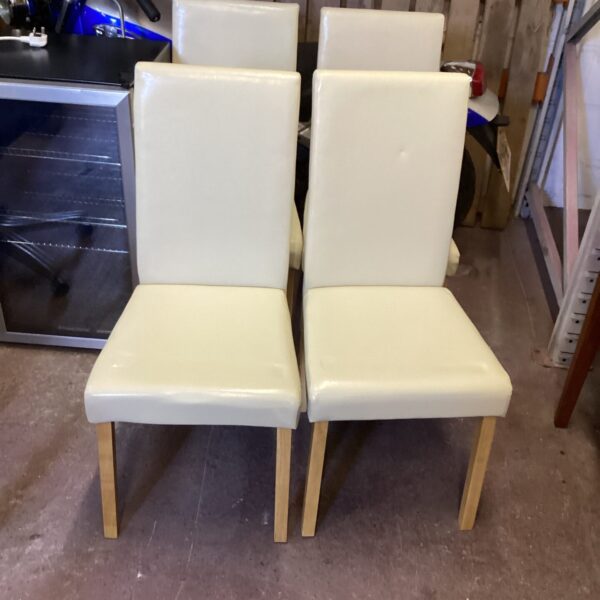 Set of four cream dining chairs with wooden legs.