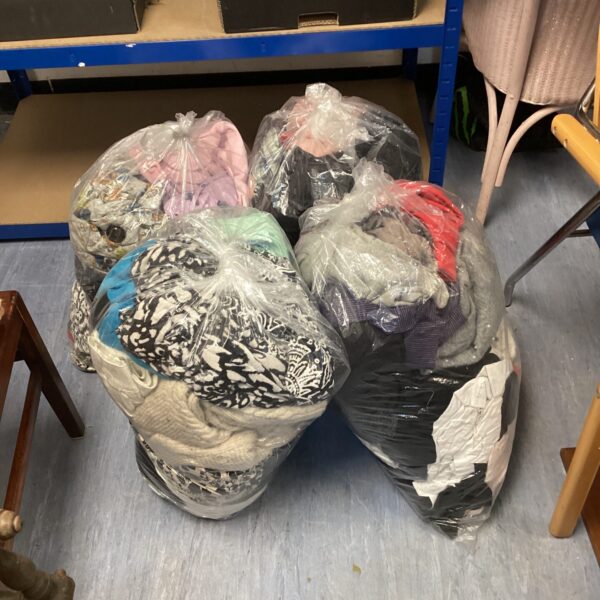 Four bags filled with a mixed clothing lot for resale.