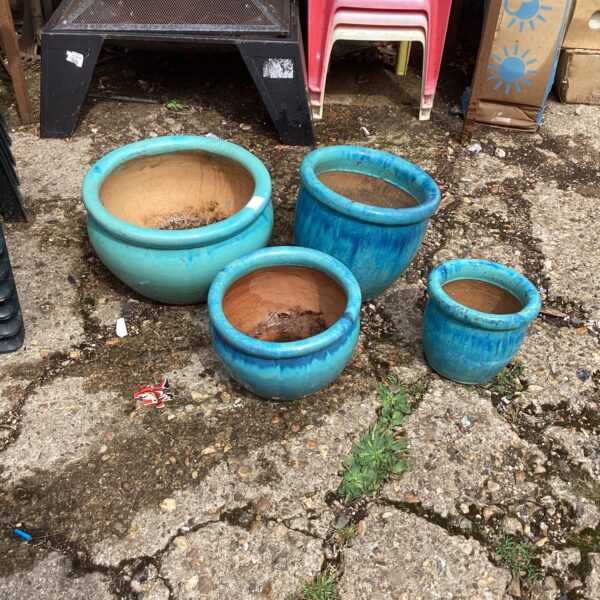 Teal glazed garden pots displayed outdoors, a set of four.
