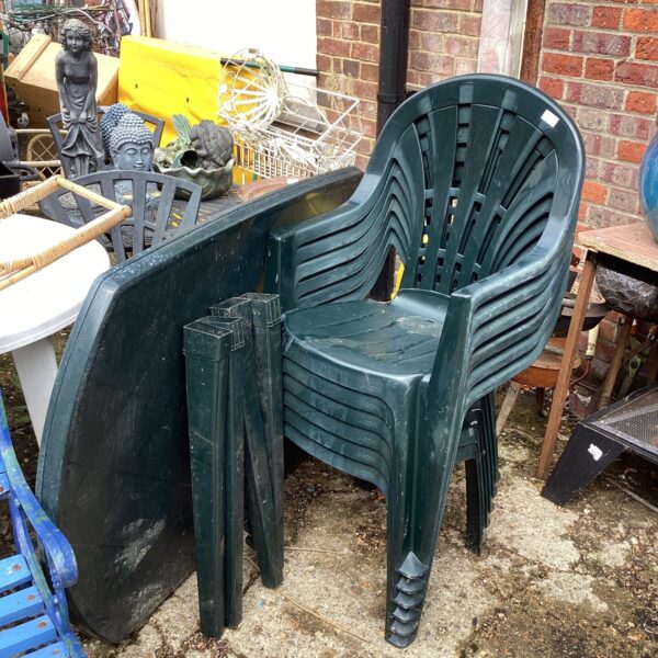 Plastic patio set with table and four chairs in a garden setting.