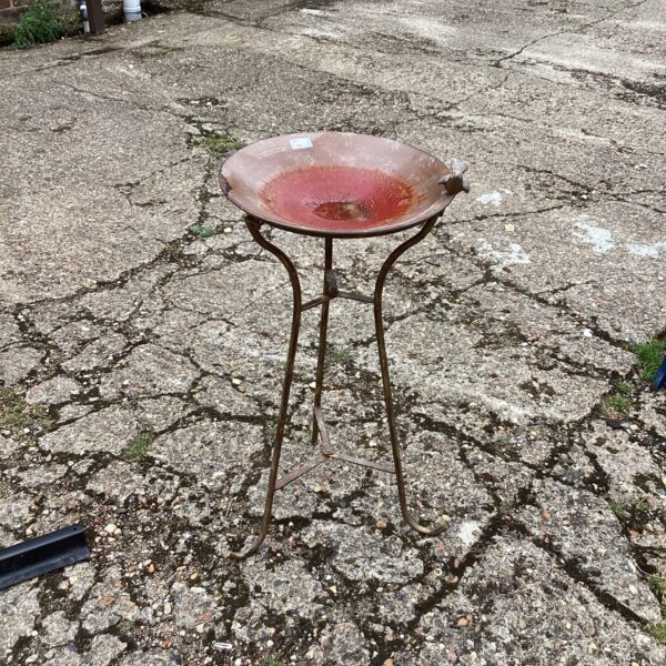Rusted vintage metal garden birdbath in an outdoor setting.