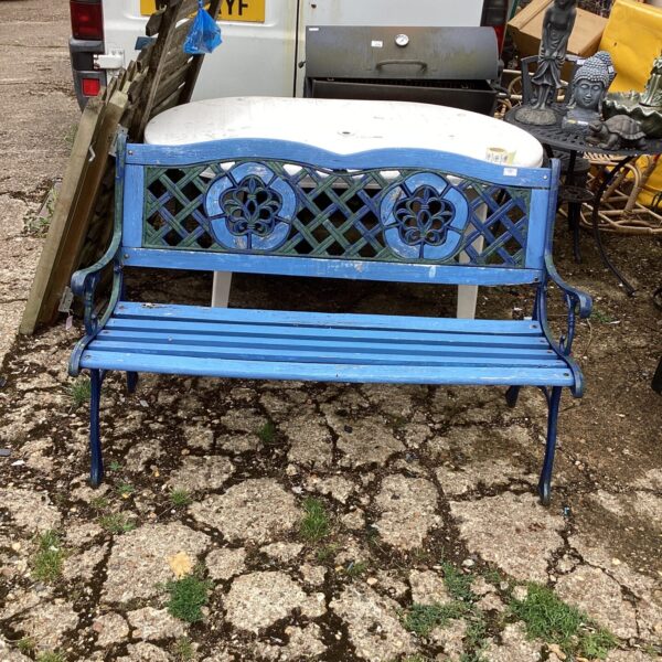 Antique wrought iron garden bench with floral backrest detail.