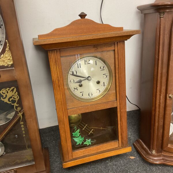 Vintage oak wall clock with pendulum, classic antique home decor.