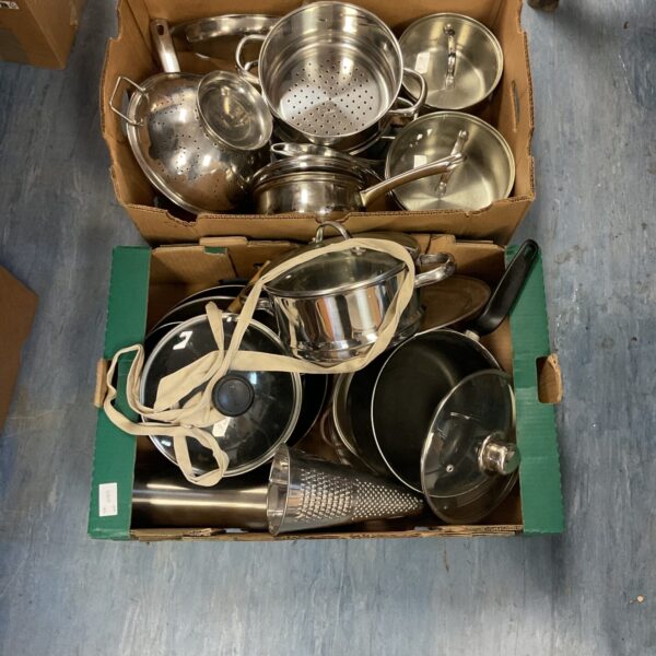 Mixed lot of stainless steel pots, pans, and lids for kitchen use.