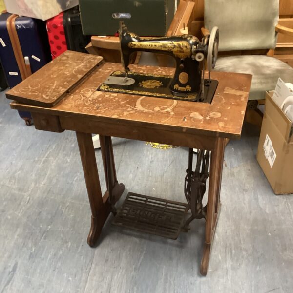 Antique Singer treadle sewing machine on wooden base.