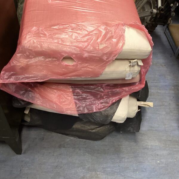 Stack of ten neutral patio chair cushions for outdoor seating.