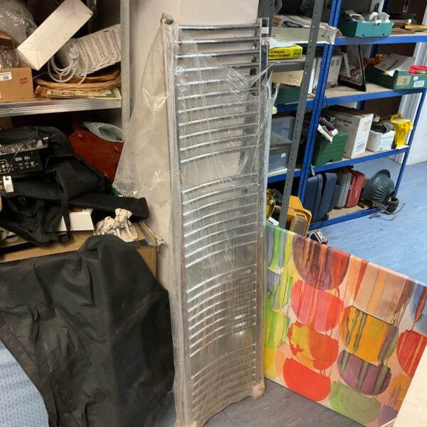 Tall chrome radiator for bathroom heating.