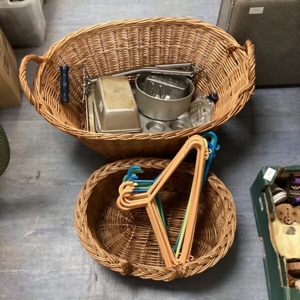 Wicker basket lot filled with baking trays and clothes hangers.