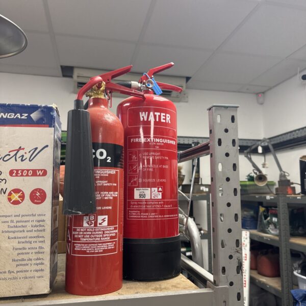 Vintage red fire extinguisher with lever and nozzle.