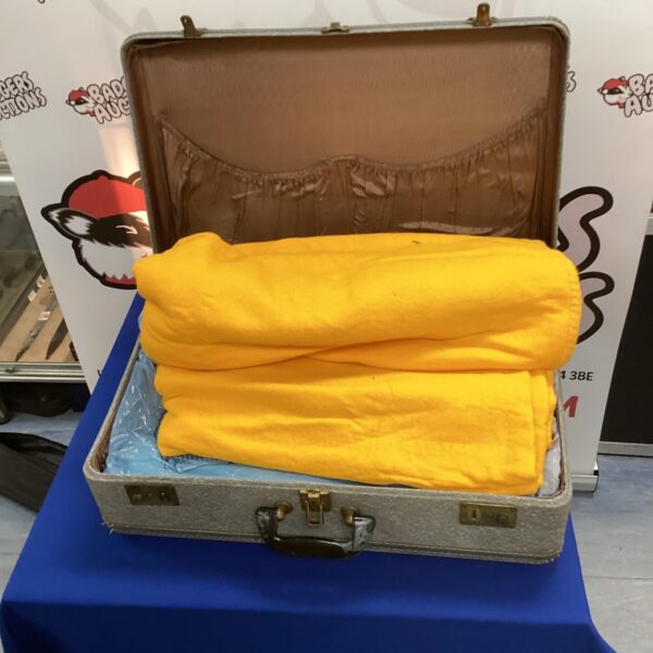 Vintage suitcase open with blankets inside, retro travel case.