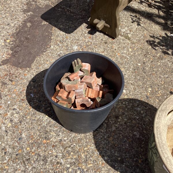 Close-up of terracotta planter feet in a black bucket.