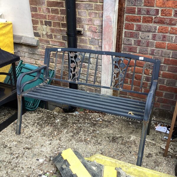 Vintage metal garden bench with floral detailing in a garden setting.