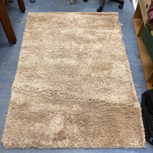 Beige shagpile rug with a deep pile texture.