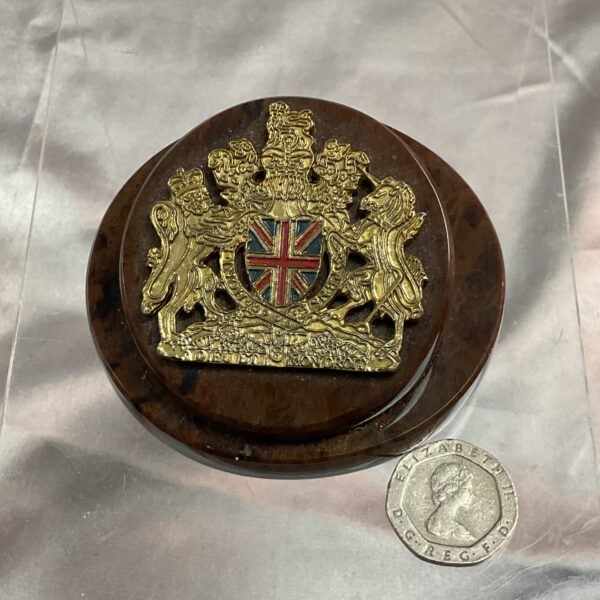 Detailed royal crest paperweight on a dark stone base.