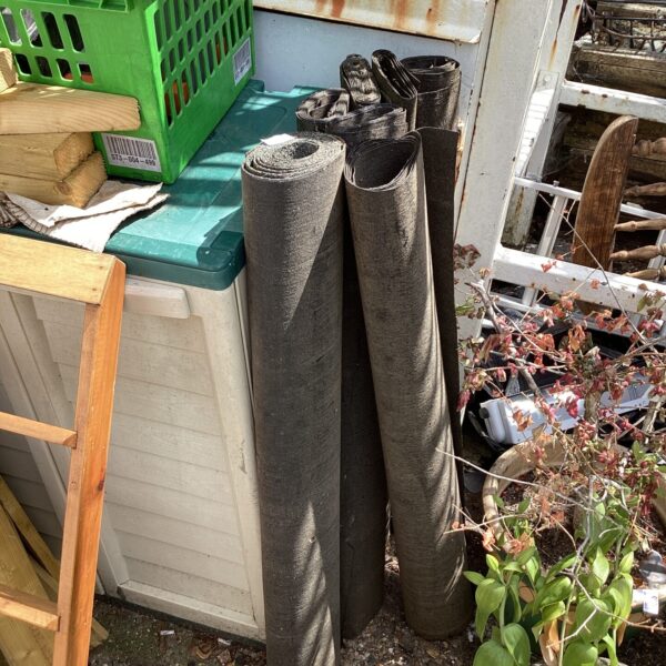 Rolls of weathered roofing felt stored outdoors.