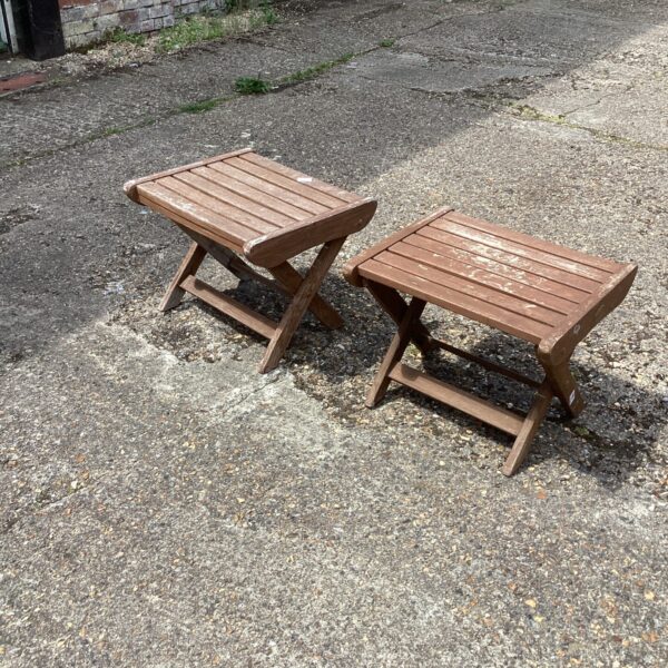 Pair of small wooden garden tables in a garden setting.