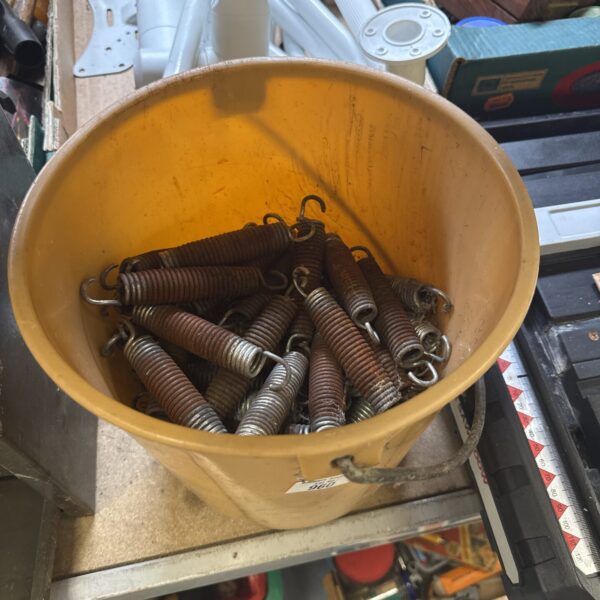 Assorted coil springs in a bucket, ideal for workshop or restoration.
