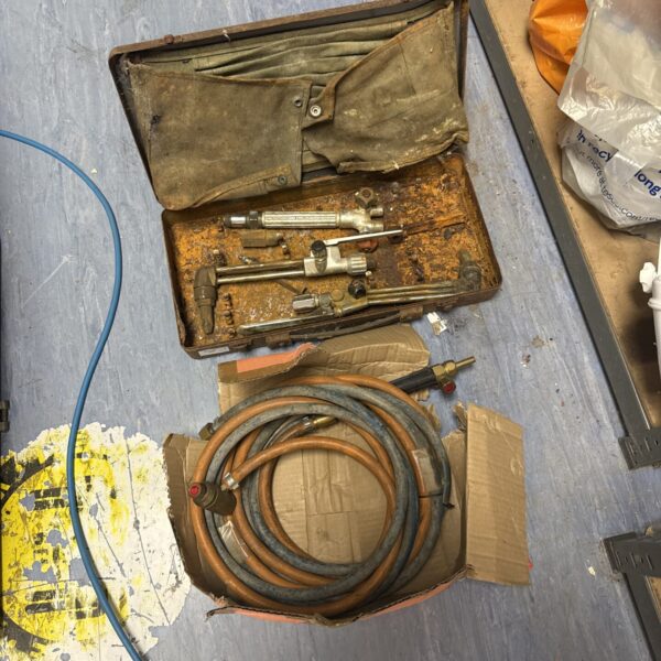 Vintage acetylene torches and hose in a worn carrying case.