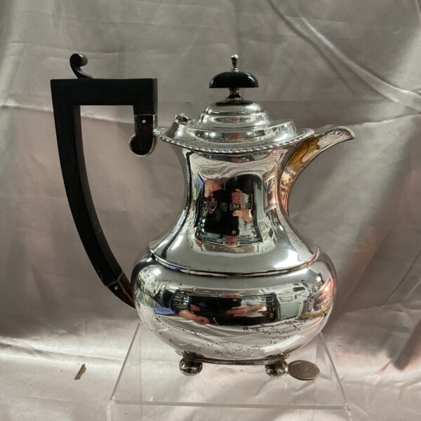 Antique sterling silver coffee pot with black handle.