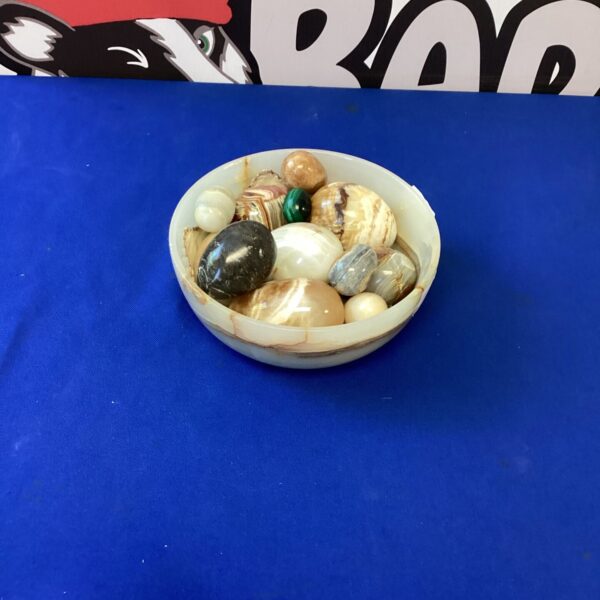 Polished onyx eggs and pebbles displayed in a decorative bowl.