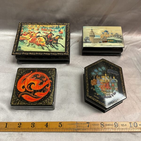 Four vintage Russian lacquerware boxes with hand-painted scenes.