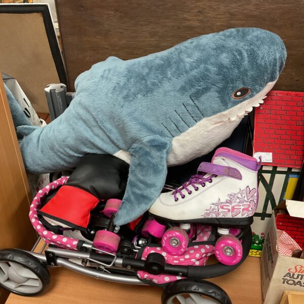 Child's toy lot featuring a dolls pram, roller skates, and plush shark.